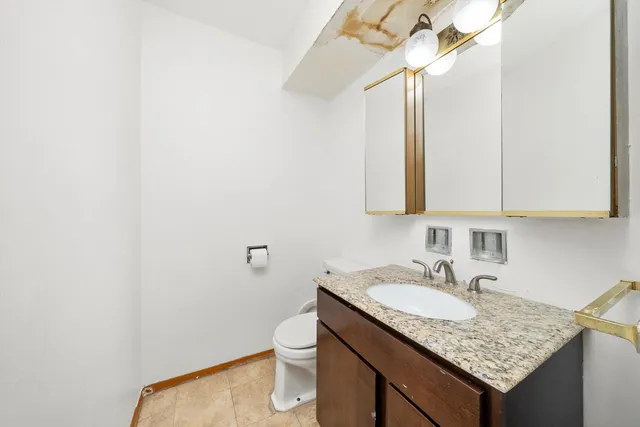 a bathroom with a granite countertop sink and a toilet
