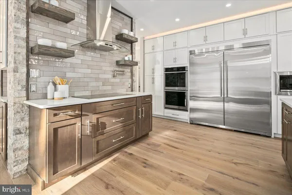 a view of a hallway with wooden floor and a bathroom