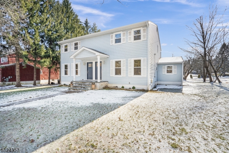 a front view of a house with a dirt yard and a large tree