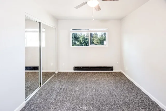an empty room with wooden floor mirror and windows