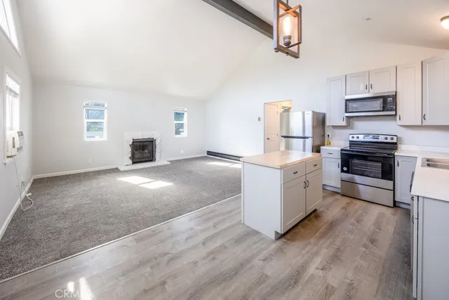 a kitchen with stainless steel appliances a stove top oven a sink a window and white cabinets