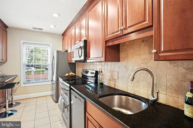 a kitchen with granite countertop a sink stainless steel appliances a counter space and cabinets