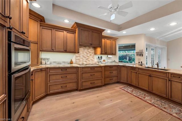 a open dining room with stainless steel appliances kitchen island granite countertop a table chairs and a refrigerator