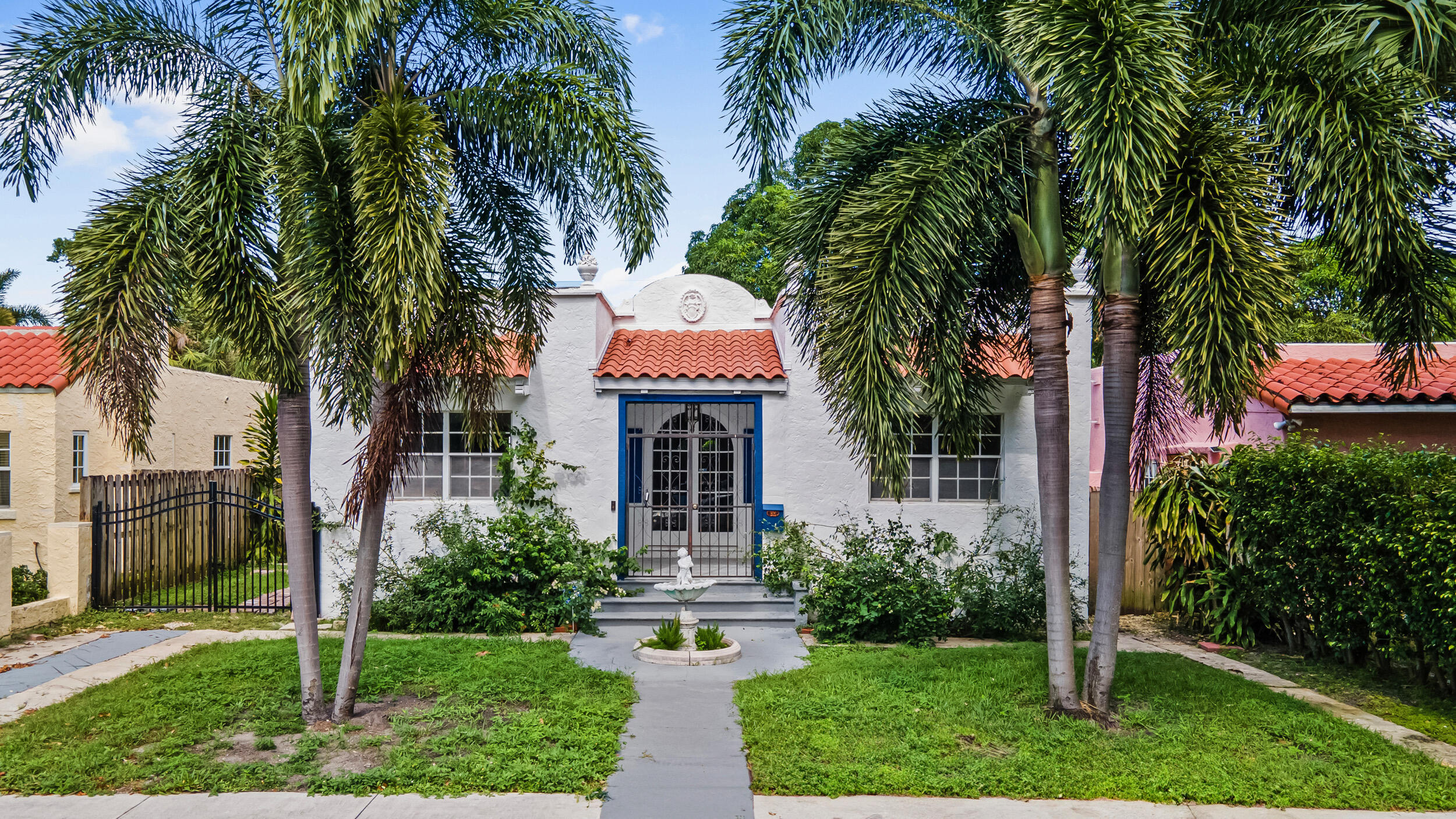 a front view of a house with a yard and palm trees