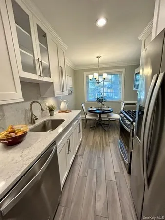 a kitchen with counter top space a sink wooden floor and stainless steel appliances
