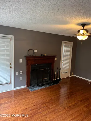 a view of an empty room with wooden floor fireplace and a window