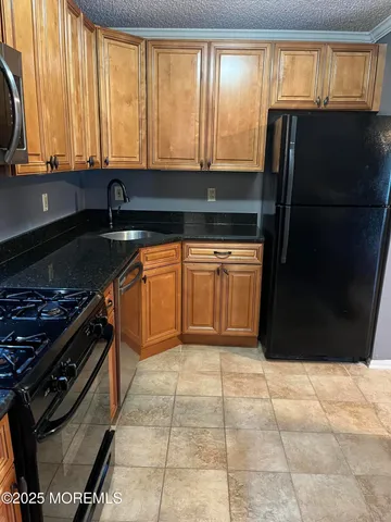 a kitchen with granite countertop a stove a sink and a refrigerator