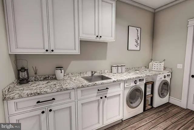 a utility room with granite countertop white cabinets and washer