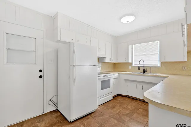 a kitchen with a sink a refrigerator and cabinets