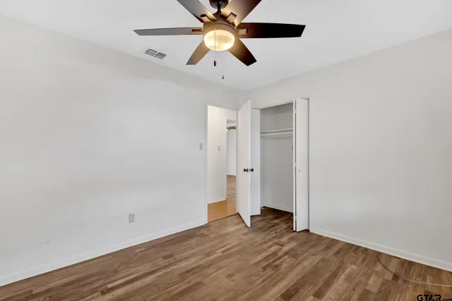 a view of a room with wooden floor and a ceiling fan