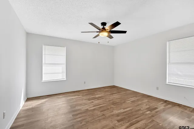 a view of a big room with wooden floor and a ceiling fan