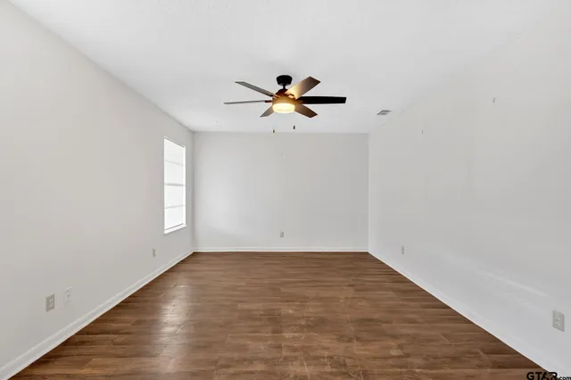 a view of a big room with wooden floor and a ceiling fan