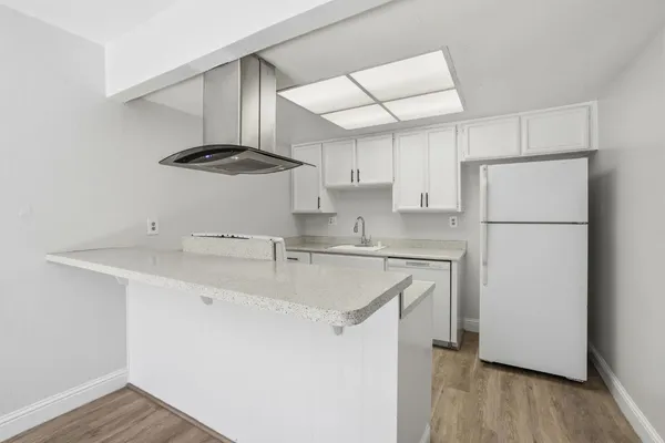 a kitchen with stainless steel appliances granite countertop a sink a stove a refrigerator and island with wooden floor