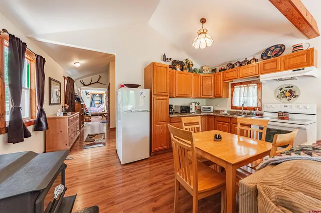 a kitchen with stainless steel appliances granite countertop a refrigerator a stove and a dining table with wooden floor