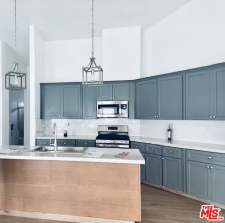 a kitchen with kitchen island granite countertop a sink cabinets and stainless steel appliances