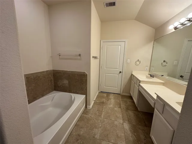 a bathroom with a tub sink and mirror