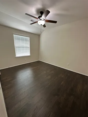 an empty room with wooden floor fan and windows