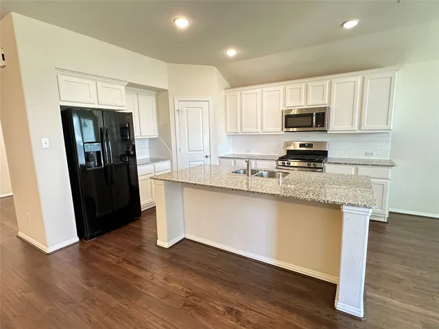 a kitchen with granite countertop a refrigerator stove and sink