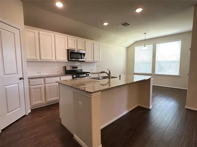 a kitchen with granite countertop a sink cabinets and a wooden floor