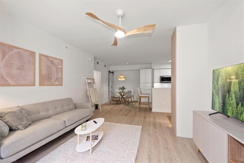 1170 Reserve Way, Unit 107 Naples, FL 34105 - Photo 11 of 47 Living area featuring light wood-style floors, a ceiling fan, and a barn door