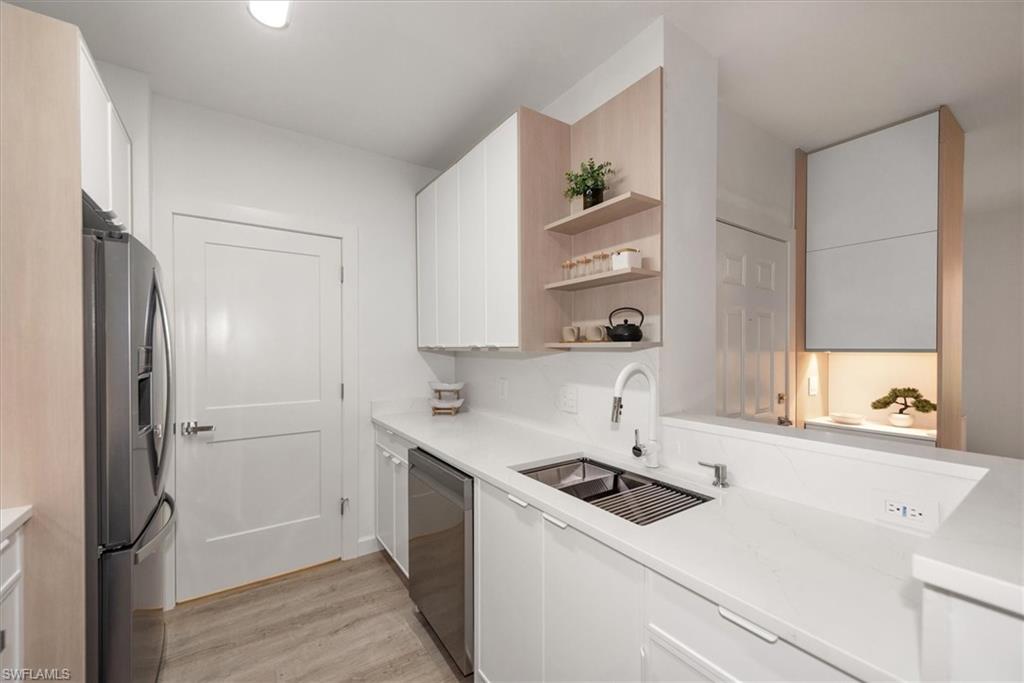 1170 Reserve Way, Unit 107 Naples, FL 34105 - Photo 14 of 47 Kitchen featuring open shelves, white cabinets, appliances with stainless steel finishes, light wood-style floors, and light stone countertops