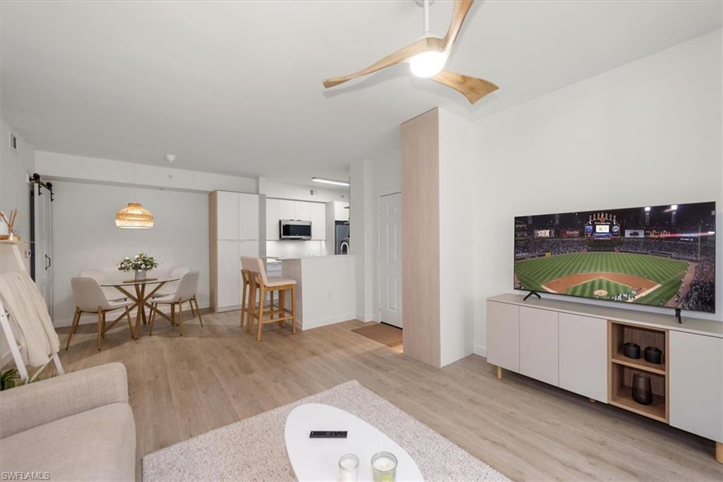 1170 Reserve Way, Unit 107 Naples, FL 34105 - Photo 10 of 47 Living area featuring a barn door, light wood-style floors, and a ceiling fan