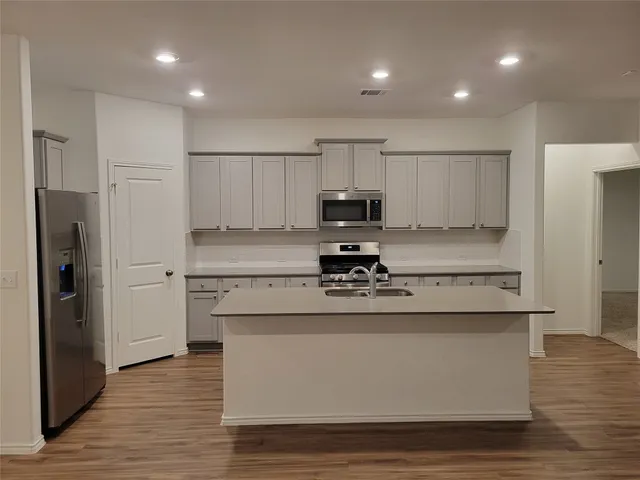 a kitchen with kitchen island stainless steel appliances cabinets and wooden floor