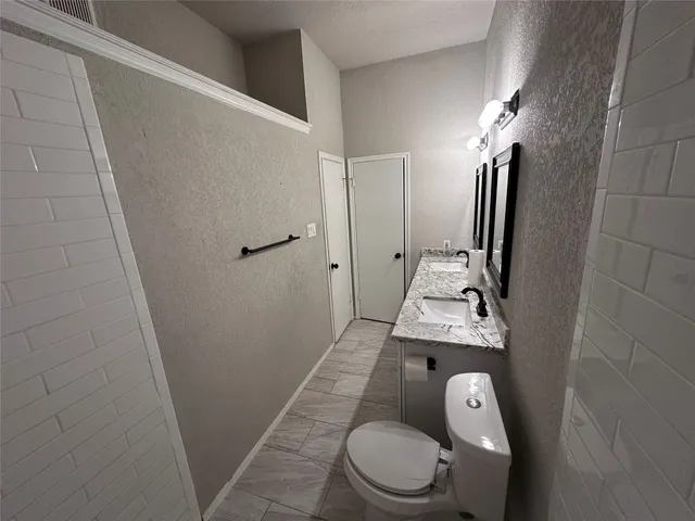 a bathroom with a granite countertop shower a toilet and a sink