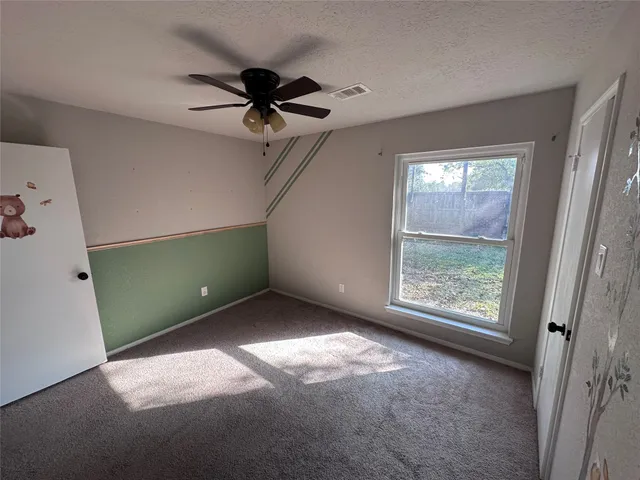 an empty room with windows and fan