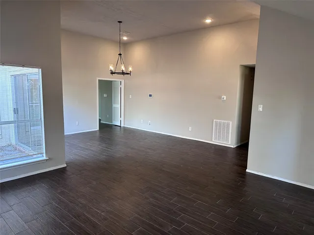 an empty room with wooden floor cabinet and windows