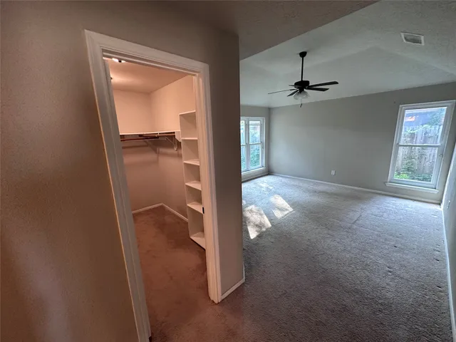 an empty room with a mirror and a ceiling fan