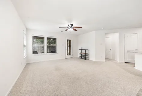 an empty room with ceiling fan and window