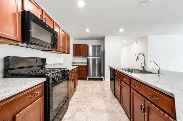 a kitchen with stainless steel appliances granite countertop a stove top oven a sink dishwasher a microwave oven and a refrigerator