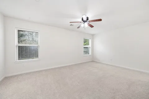 an empty room with windows and fan