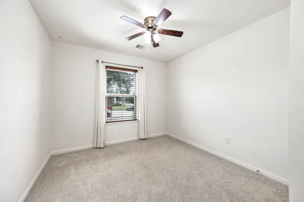 an empty room with chandelier fan and windows