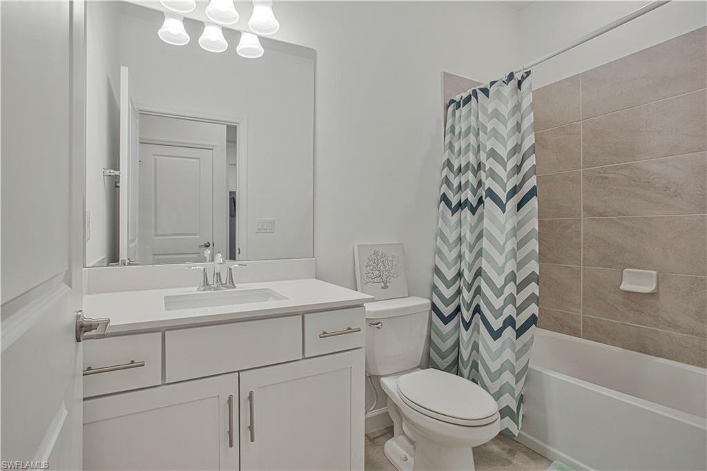 18293 Ridgeline Drive Estero, FL 33928 - Photo 18 of 47 a bathroom with a sink a toilet a mirror a vanity and a bathtub