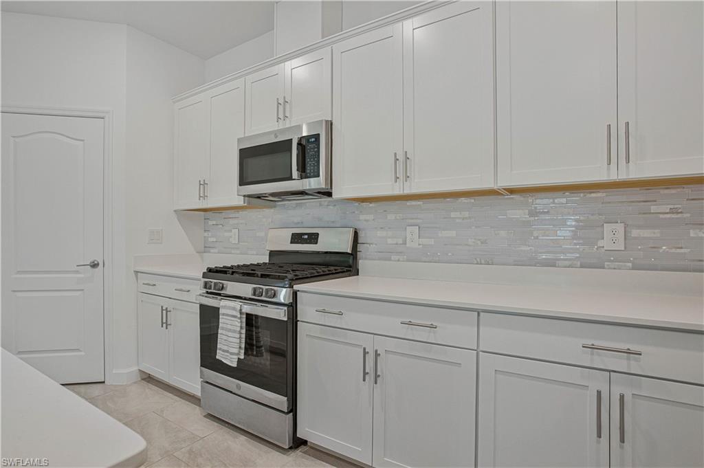 18293 Ridgeline Drive Estero, FL 33928 - Photo 6 of 47 a kitchen with white cabinets and stainless steel appliances