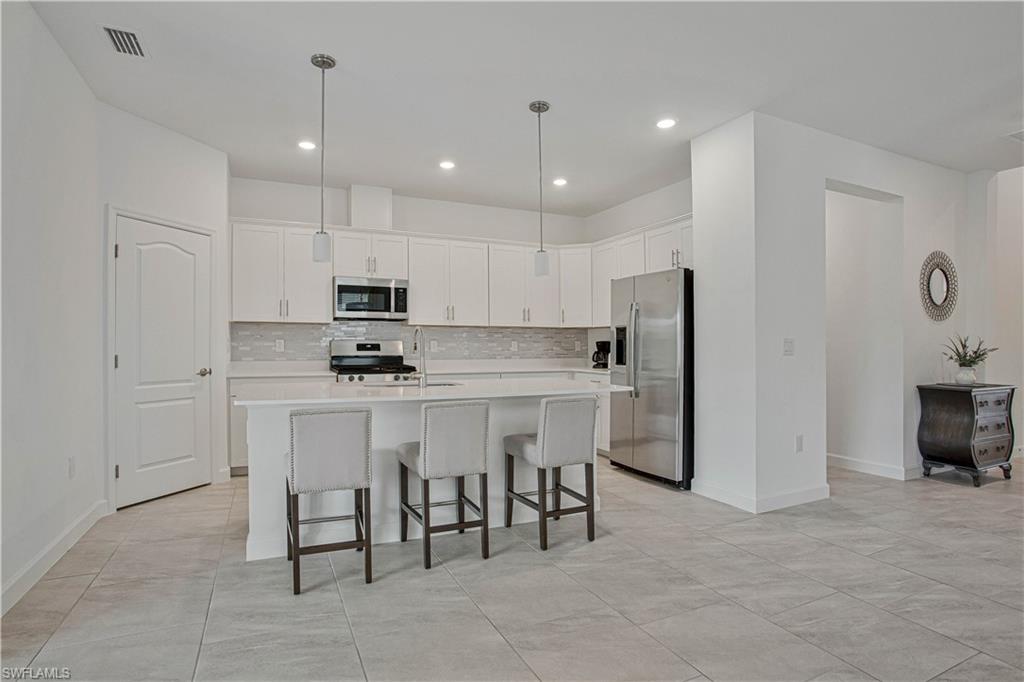 18293 Ridgeline Drive Estero, FL 33928 - Photo 7 of 47 a kitchen with kitchen island white cabinets and stainless steel appliances