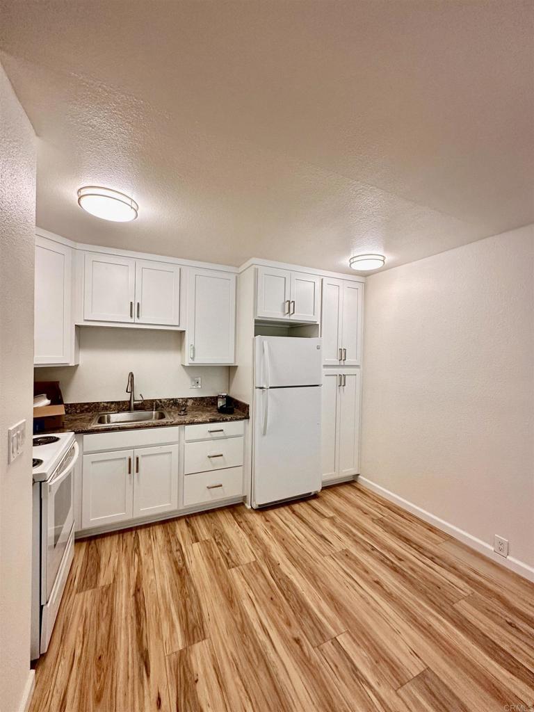 6394 Rancho Mission Road San Diego, CA 92108 - Photo 1 of 14 a kitchen with granite countertop white cabinets and white appliances