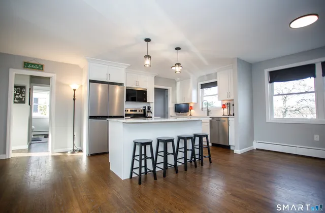 a kitchen with stainless steel appliances granite countertop a stove top oven a sink dishwasher a dining table and chairs with wooden floor