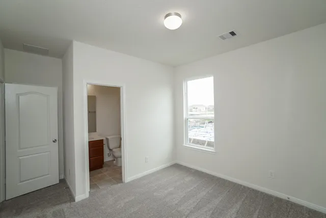 a view of an empty room with closet and a window