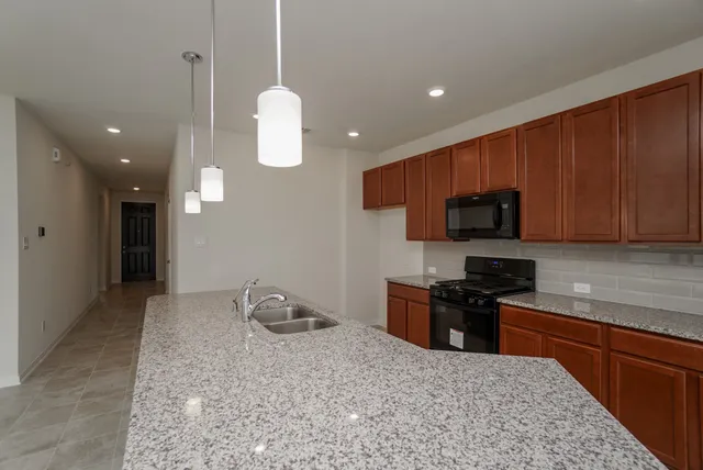 a kitchen with granite countertop stainless steel appliances a stove a sink and a microwave