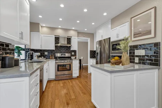 a kitchen with kitchen island white cabinets and stainless steel appliances