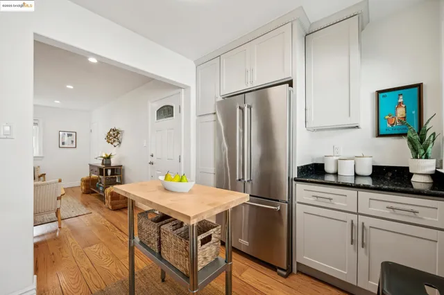 a kitchen with stainless steel appliances a refrigerator a sink a stove and white cabinets