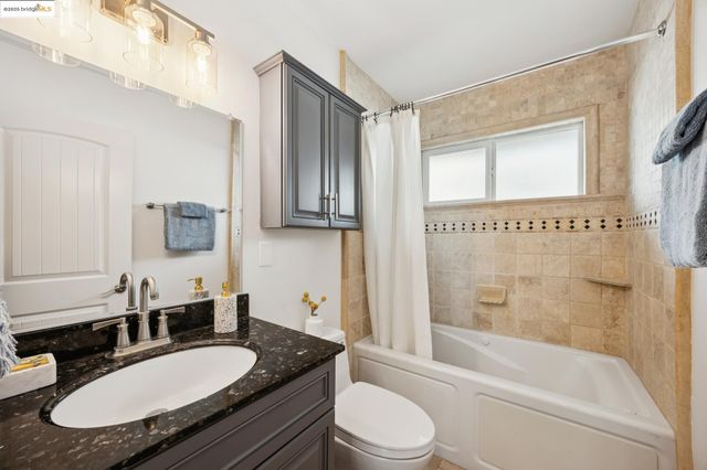 a bathroom with a granite countertop sink mirror toilet and bathtub