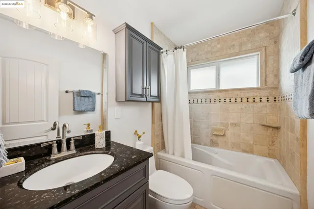a bathroom with a granite countertop sink mirror toilet and bathtub