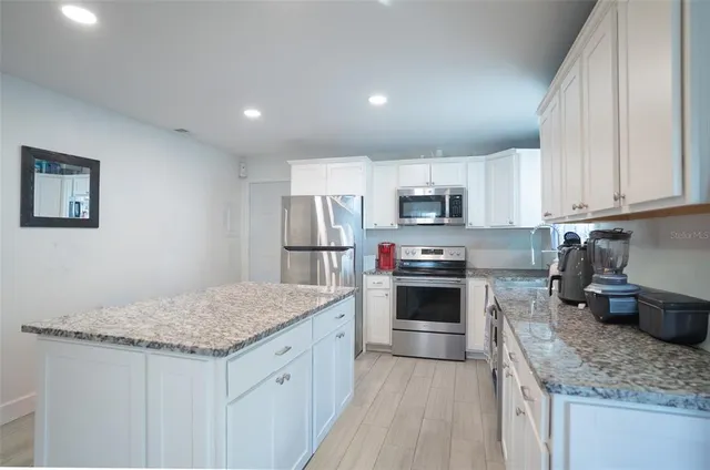 a kitchen with granite countertop a sink and white cabinets