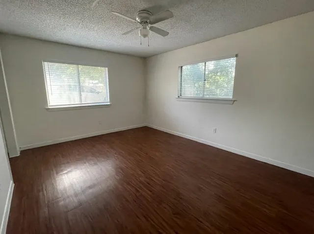 a view of empty room with wooden floor and fan