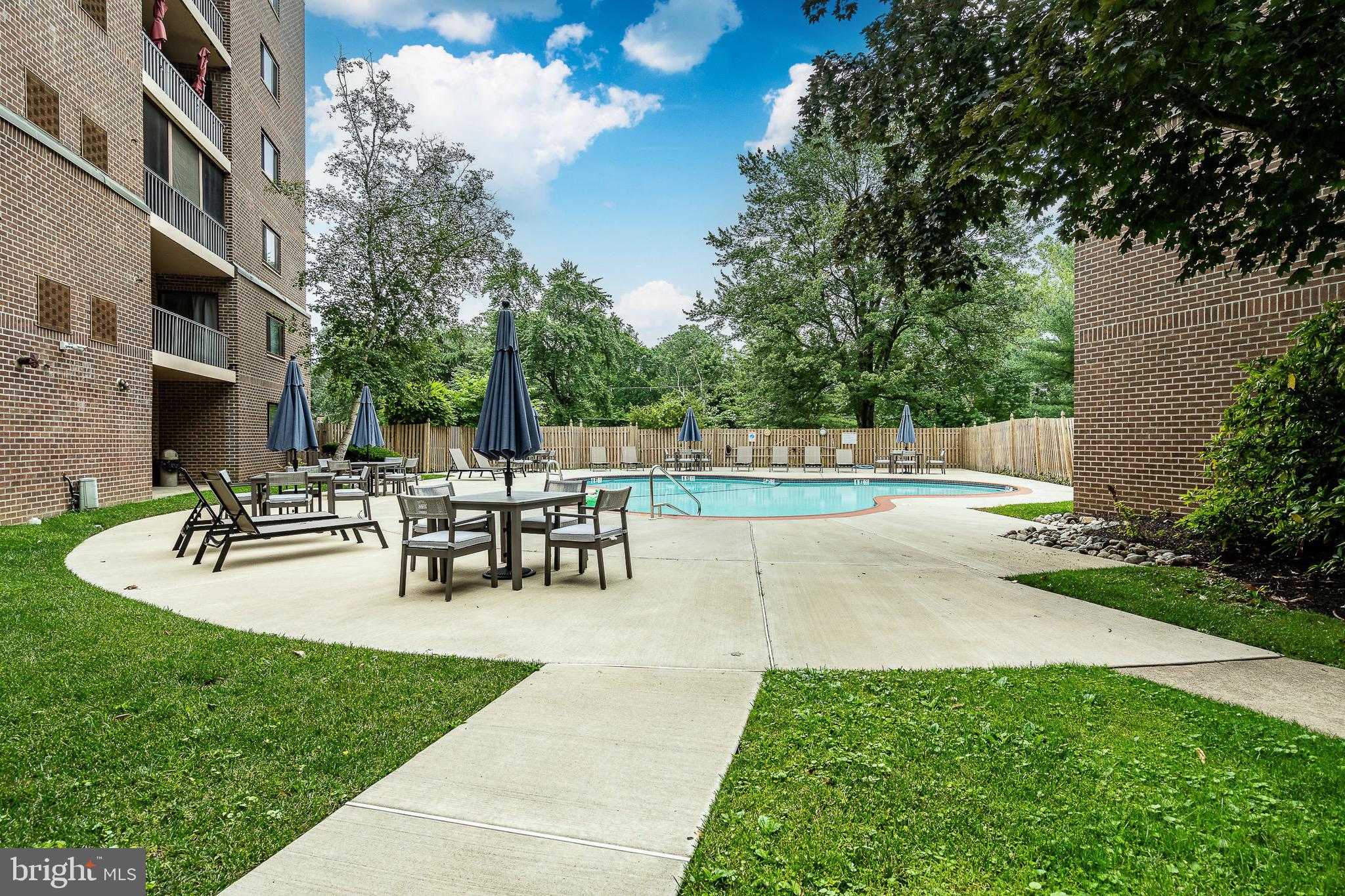 1219 West Wynnewood Road, Unit 105 Wynnewood, PA 19096 - Photo 27 of 34 a view of a patio with table and chairs potted plants and large tree