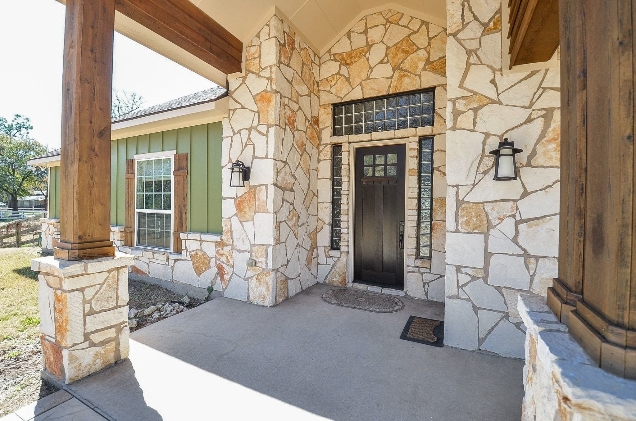 13327 Little Ranch Road Cypress, TX 77429 - Photo 11 of 49 This home features a charming entrance with rustic stonework and wood accents. The front porch includes a solid wood door framed by glass panels, under a covered entryway, offering a welcoming and stylish exterior.
